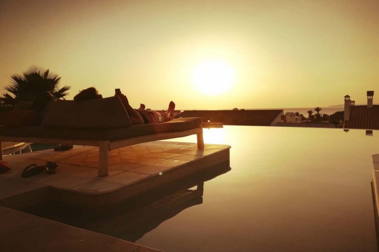 personas tumbadas en hamacas viendo el atardecer en la piscina infinity del hotel el cortijo de zahara