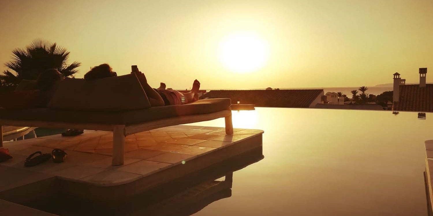 personas tumbadas en hamacas viendo el atardecer en la piscina infinity del hotel el cortijo de zahara