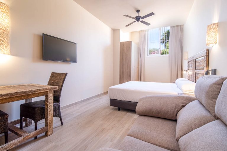 apartamento turístico con cama doble, televisión, sofá y mesa en tarifa
